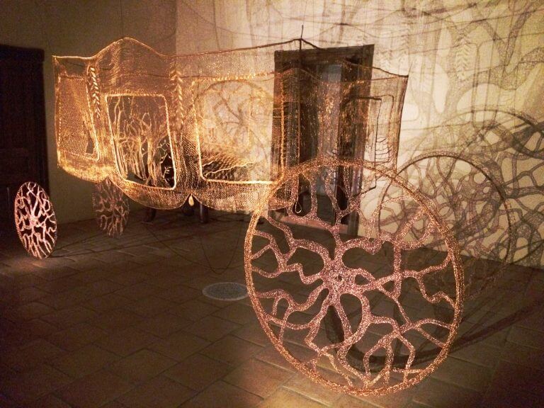 Lieve Jerger, Carriage of Lost Love, 1977-Present, copper wire, steel wheel frames, Belgian bobbin lace, 6 ft. X 13.5 ft. X 6.5 ft. Courtesy of the artist.