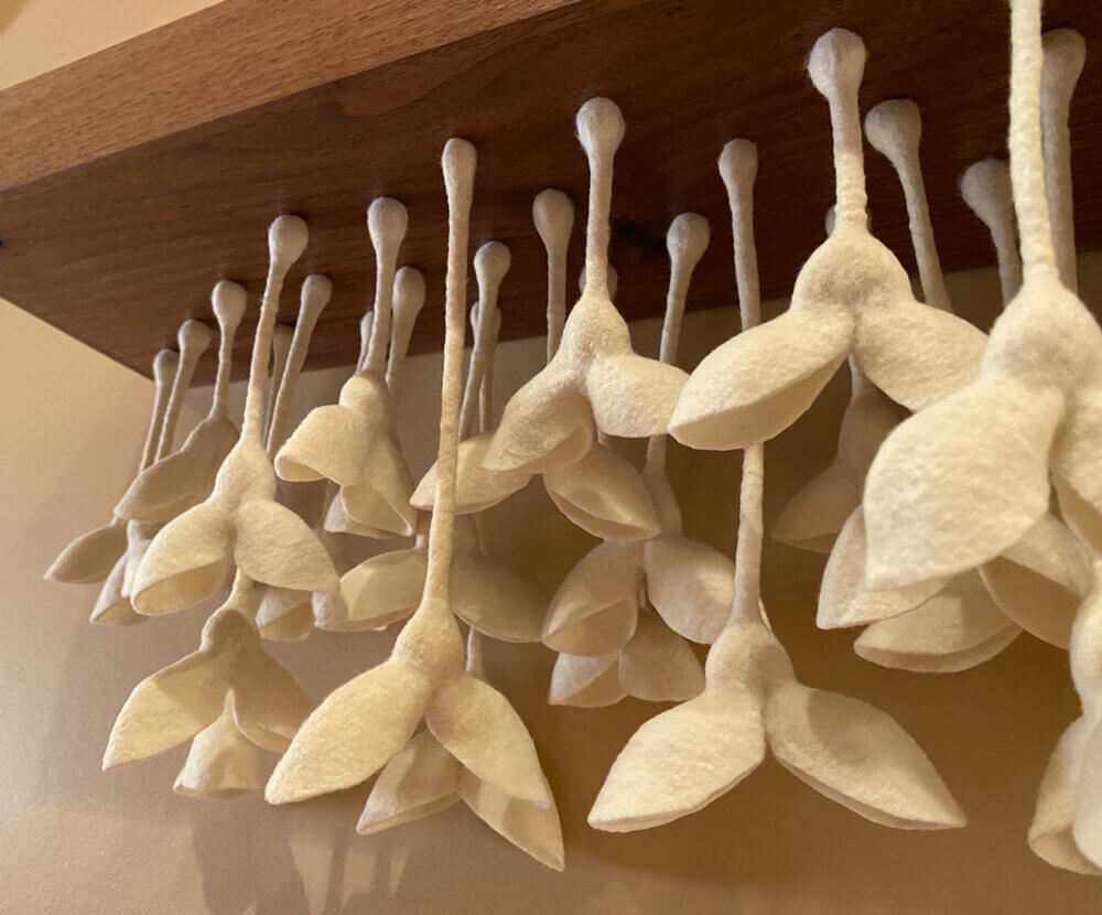 Close-up of 'Seedbed': wool shapes hang from a wood board.